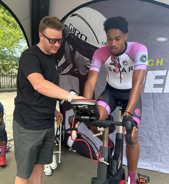 Cyclist riding watt bike, man is explaining to the cyclist his results.