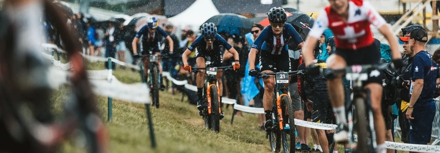 A pack of mountain bikers racing in a race across a grassy area