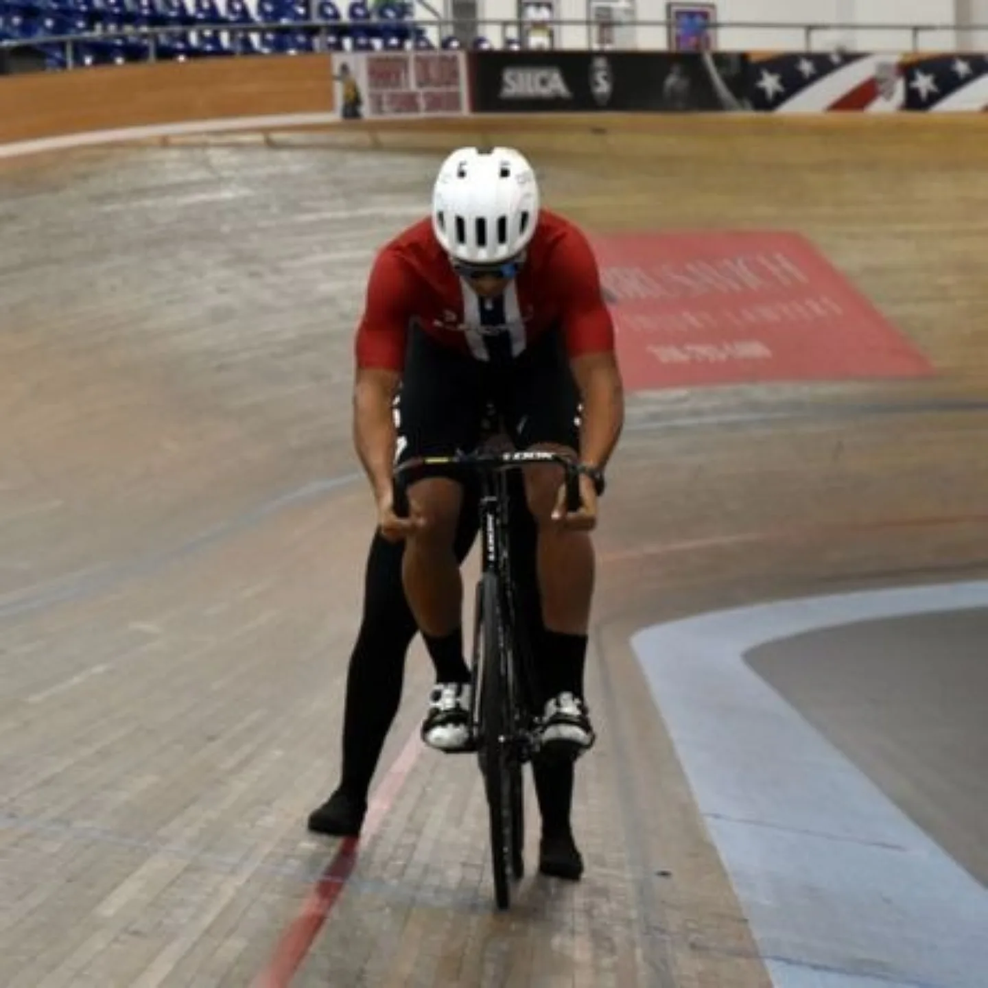 Man on track bicycle in velodrome.