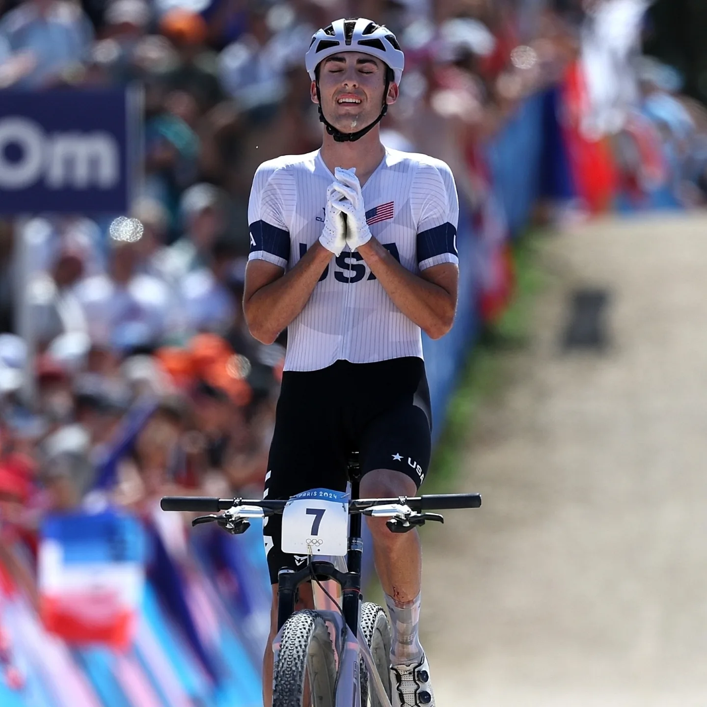 Men's mountain bike finals with rider holding his hands in a praise position over his heart.
