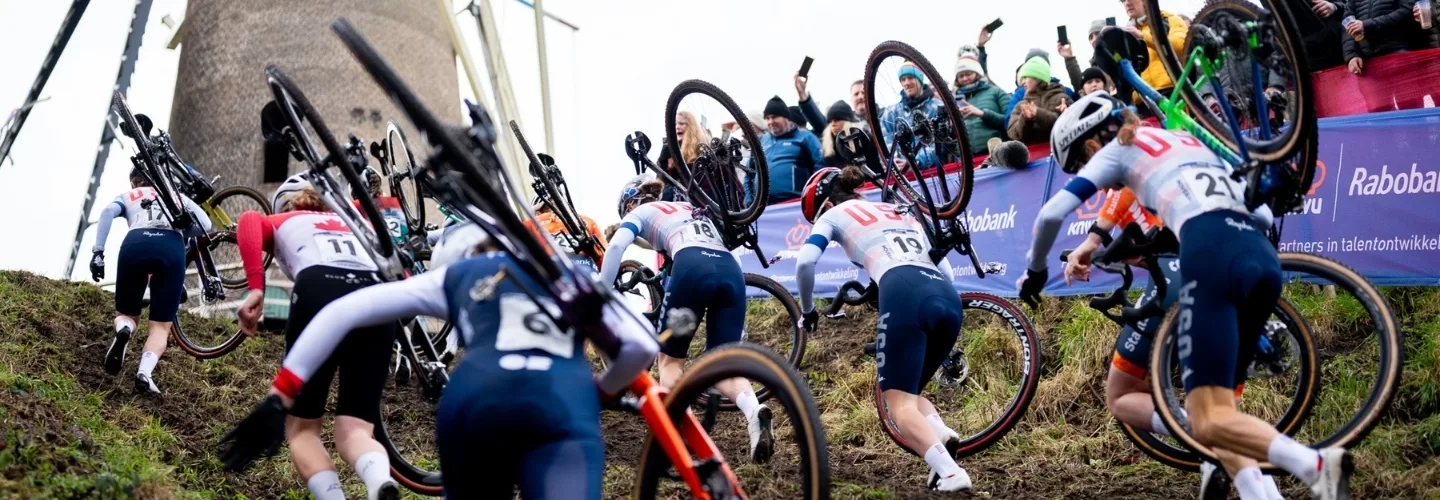 Cyclocross racers running up a hill while carrying their bikes