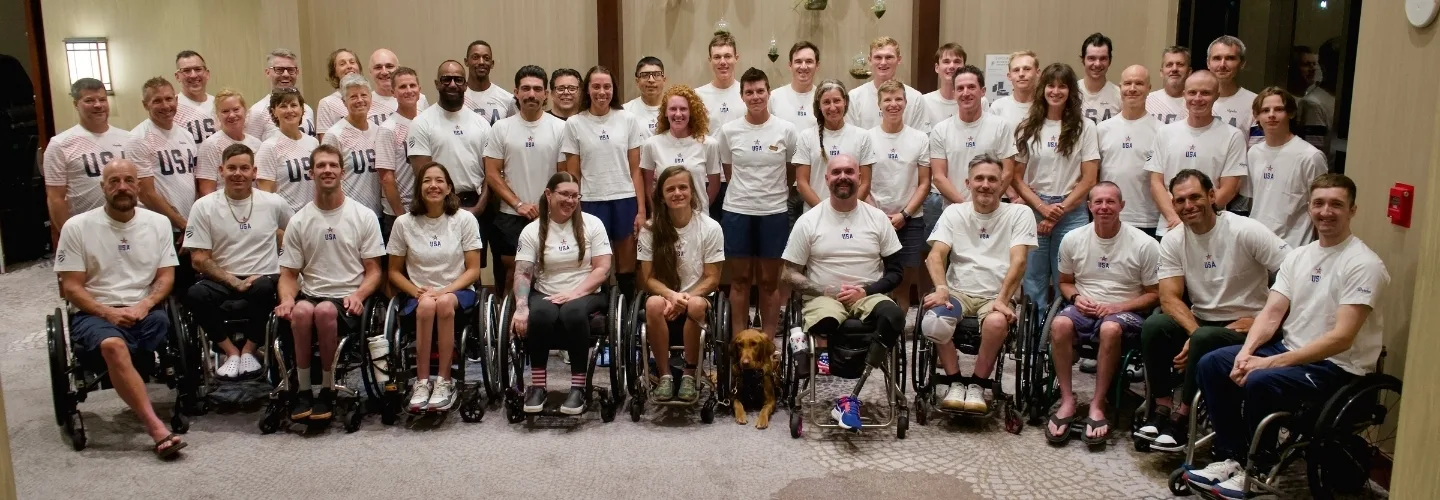 Group photo of Team USA athletes and staff, including several wheelchair users, posing together at an event