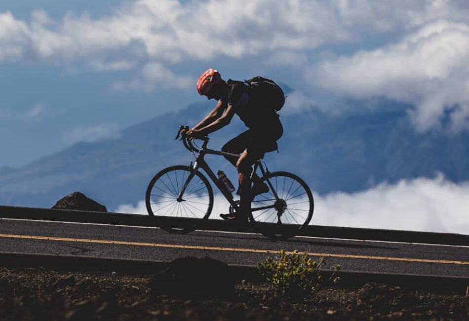 A solo shot of a road cyclist biking uphill.